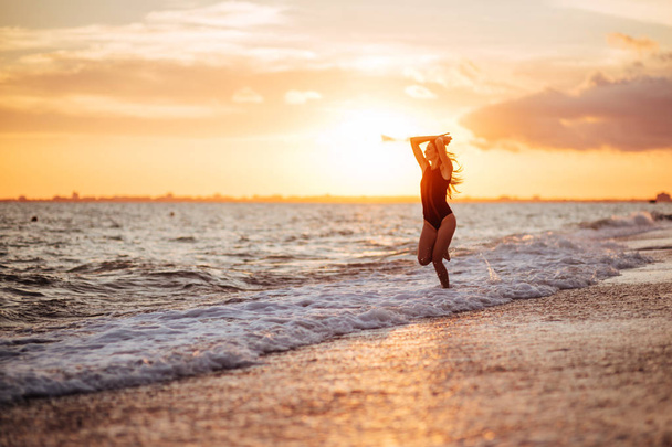 Mujer despreocupada bailando al atardecer en la playa. Vacaciones vitalidad concepto de vida saludable - Foto, Imagen