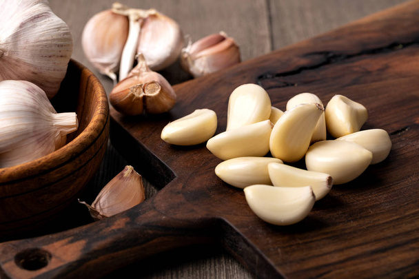 Garlic Cloves and Bulb in vintage wooden bowl - Фото, изображение