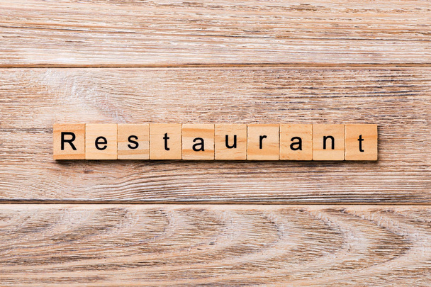 Το εστιατόριο λέξη γραμμένη σε ξύλινο φραγμό. Το εστιατόριο κείμενο σε ξύλινο τραπέζι για το desing, έννοια. - Φωτογραφία, εικόνα