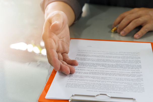 Бизнесмен предлагает договорной документ своему деловому партнеру для подписания договора
 - Фото, изображение