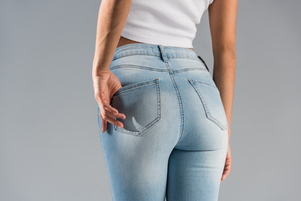 Cropped view of shapely girl in blue jeans isolated on grey - Photo, Image