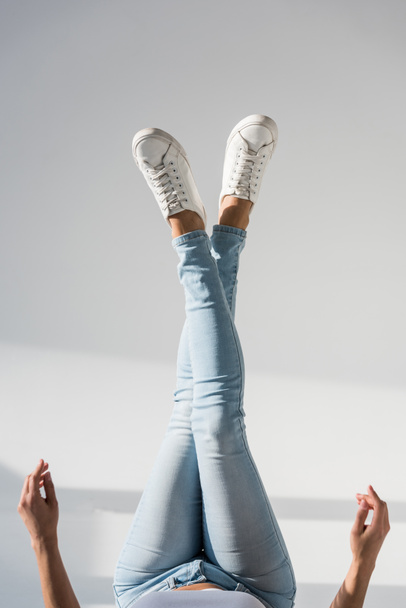 Partial view of woman in blue jeans on grey background - Fotoğraf, Görsel