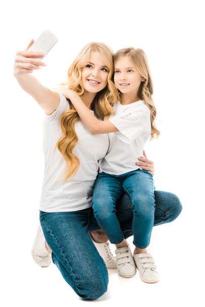 happy mother taking selfie while hugging daughter isolated on white - Фото, изображение
