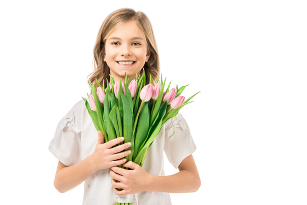 adorable smiling child with beautiful pink tulips isolated on white - Fotó, kép