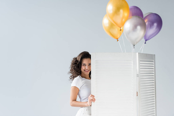 Piękna dziewczyna kręcone z balonów, uśmiechając się na szarym tle - Zdjęcie, obraz