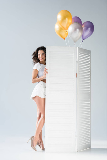 Szczęśliwa dziewczyna w wysokich obcasach z balonów, stojąc na szarym tle - Zdjęcie, obraz