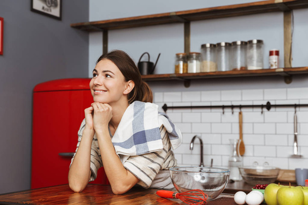Happy young woman standing at the kitchen at home - Photo, Image
