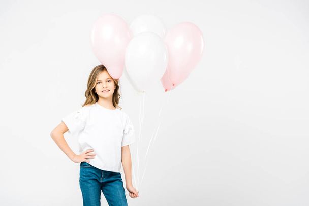 smiling child with hand on hip holding air balloons on white background - Photo, Image