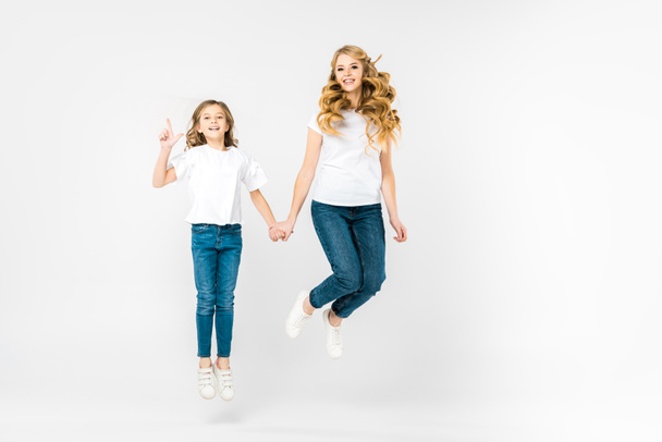 happy mother with adorable daughter jumping on white background - Foto, imagen