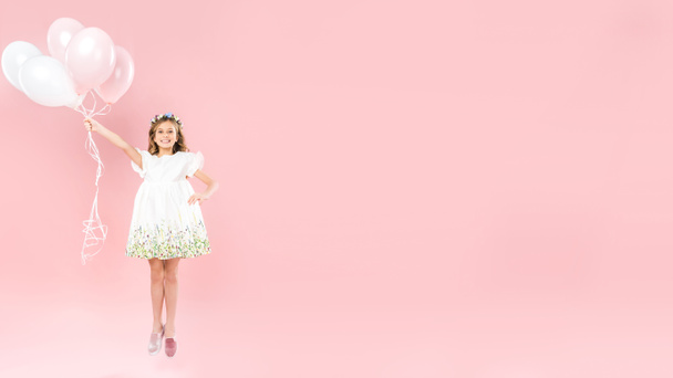 criança alegre pulando com balões de ar festivo no fundo rosa com espaço de cópia
 - Foto, Imagem
