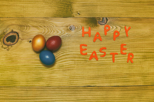 Feliz mensaje de Pascua con huevos pintados en la mesa de madera.Foto tonificada
. - Foto, Imagen
