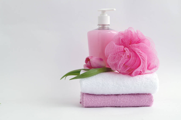 Nestemäinen saippua ja kaksi pyyhettä valkoisella pohjalla
 - Valokuva, kuva