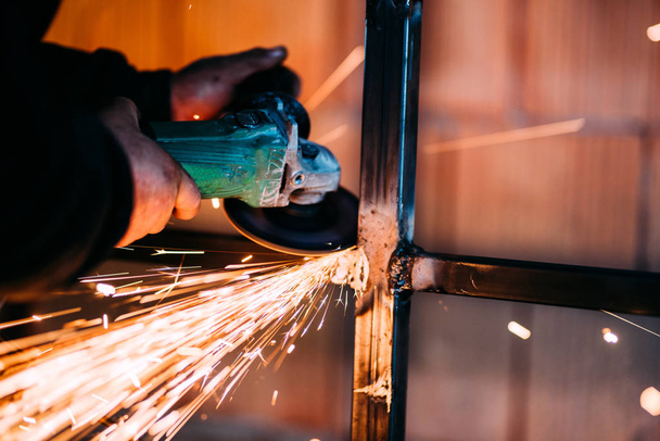 construction site details with worker hands cutting and using angle grinder - 写真・画像