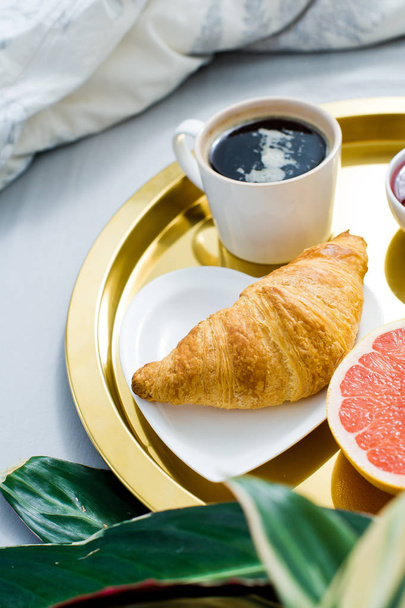 Classic French Breakfast in bed, home decor. Coffee, jam, croissant, orange juice, grapefruit, lychee. Side view, light background, close up - Fotografie, Obrázek