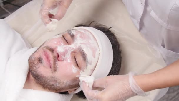 Concepto de servicios cosméticos y de spa. Hombre joven con máscara facial de arcilla en spa de belleza
 - Metraje, vídeo