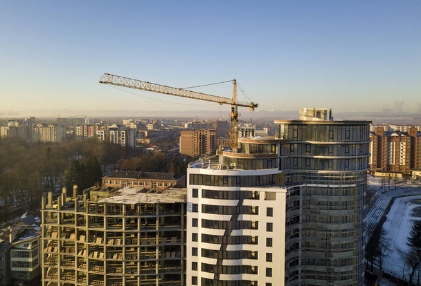Apartman vagy office magas épület építés alatt, felülnézet. Toronydaru a ragyogó kék ég másol helyet a háttér, nyúlik, horizon city táj. Drone légifényképezés. - Fotó, kép