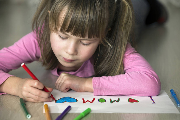 Cute child girl drawing with colorful crayons I love Mom on white paper. Art education, creativity concept. - Fotoğraf, Görsel