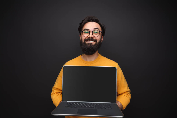 Glad man showing modern laptop - Фото, изображение
