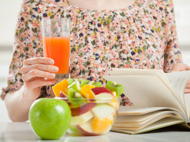 Bir kitap okuma ve meyve öğle yemeği tanınmaz halde genç kadın - Fotoğraf, Görsel