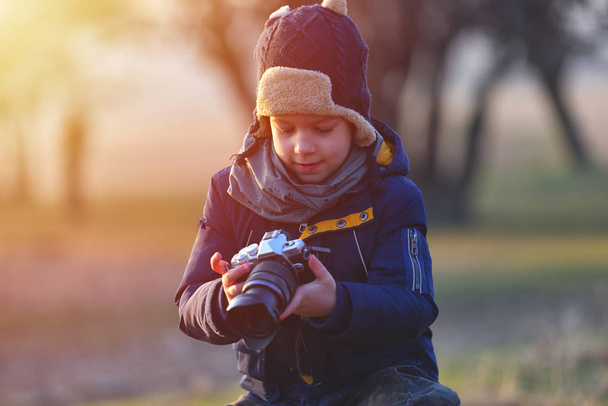 Twórcze dziecko, dziecko fotograf (mały chłopiec) z kamerą, robienia zdjęć krajobrazu w ciepłe światło zachód słońca - Zdjęcie, obraz