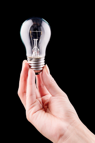 Hand holding light bulb isolated on black - Zdjęcie, obraz
