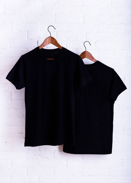 Black blank t-shirt, clothes hanging on a clothes hanger white brick wall background. Advertising discount mock up. - Φωτογραφία, εικόνα