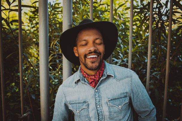 Happy attractive African American male hipster wearing black hat and jeans shirt. Street wear fashion black man . Lifestile concept. - Photo, image