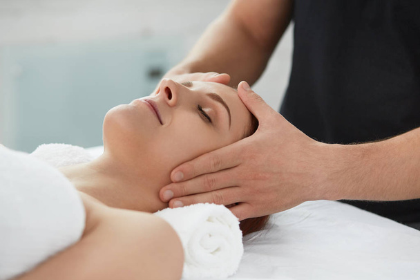 Young beautiful woman enjoying anti-aging facial massage.Male therapist making head massage to female client.Professional masseur.Relaxation,beauty,spa,body and face treatment concept.  - Foto, immagini
