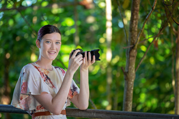 Szép mosolygó lány fotózni egy napfényes kertben őt digitális fényképezőgép - Fotó, kép