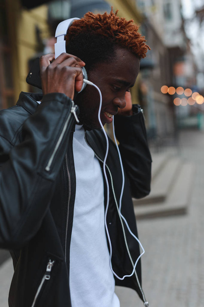 African american man listening to music in headphones at city - Fotó, kép