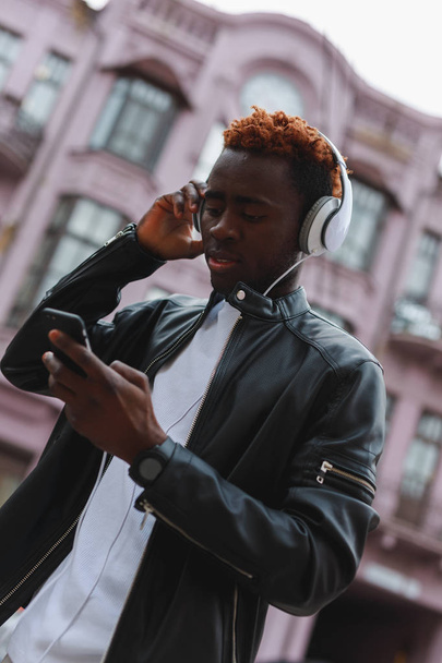 African american man listening to music in headphones at city - Foto, Imagen