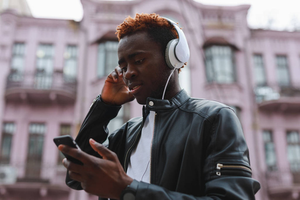 African american man listening to music in headphones at city - Zdjęcie, obraz