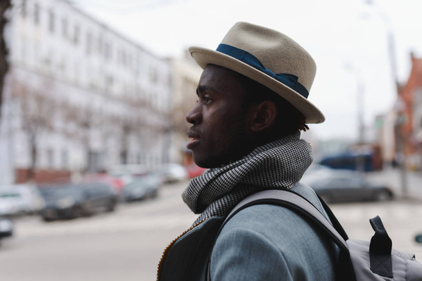 Fashion model african american man in coat and hat walking along city street - Fotoğraf, Görsel