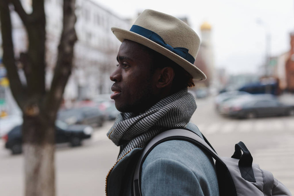 Fashion model african american man in coat and hat walking along city street - Photo, Image