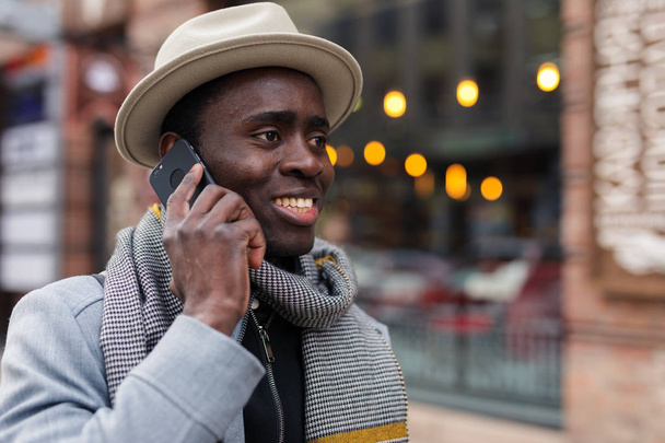 Счастливый африканский американец разговаривает со своим другом на смартфоне, гуляя по городу.
 - Фото, изображение