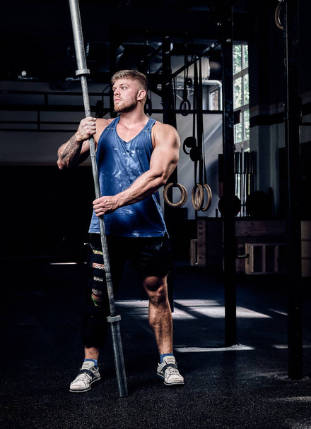 Powerlifter avec un bandage sur une jambe, tient l'haltère, se réchauffe avant l'entraînement dans la salle de gym, récupération des blessures
 - Photo, image