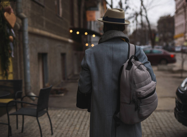 African american man in coat and hat walking along city street, back view - Zdjęcie, obraz