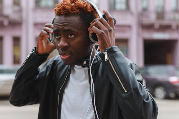 African american man listening to music in headphones at city - Valokuva, kuva