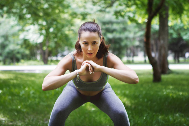 Leuke jonge vrouw doen yoga oefeningen in groen park - Foto, afbeelding