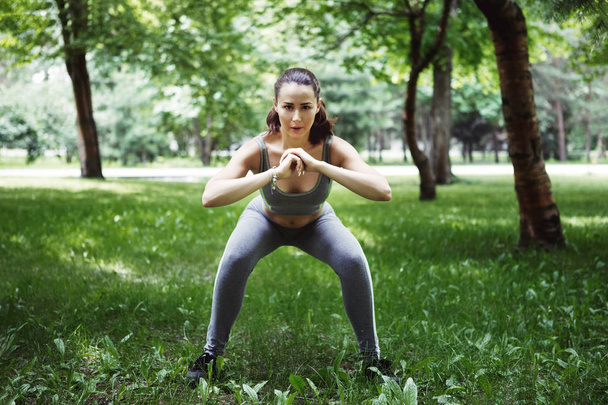 Leuke jonge vrouw doen yoga oefeningen in groen park - Foto, afbeelding