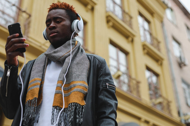 African american man listening to music in headphones at city - Foto, Imagen