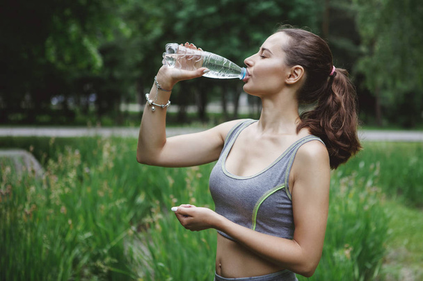 молодая красивая женщина пьет воду из бутылки во время пробежки
  - Фото, изображение