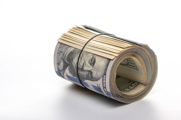 100 dollar bills twisted in buis en gebonden met een elastische band. witte achtergrond. Close-up - Foto, afbeelding