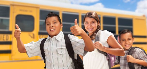 Giovani ragazzi ispanici e ragazza che camminano vicino a scuolabus
. - Foto, immagini