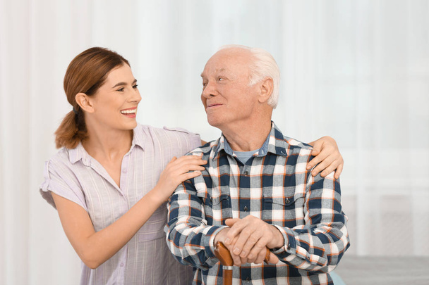 Elderly man with female caregiver at home - Foto, afbeelding