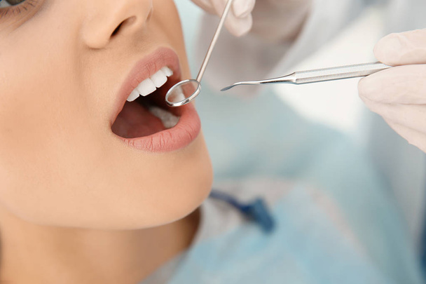 Dentist examining patient's teeth in modern clinic, closeup - Foto, imagen