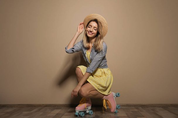 Young woman with retro roller skates against color wall - Foto, immagini