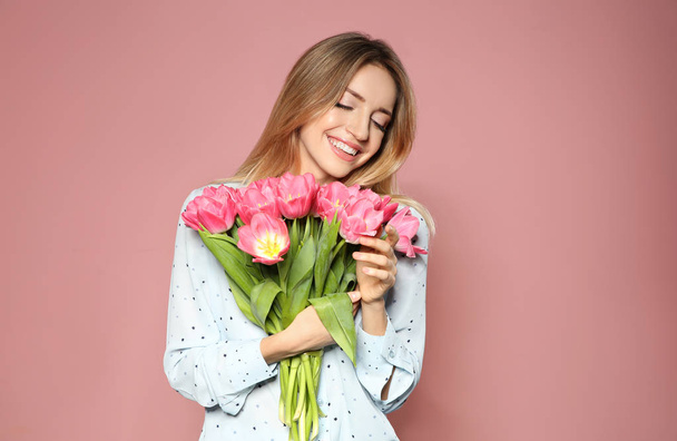 Portrait of beautiful smiling girl with spring tulips on pink background. International Women's Day - Zdjęcie, obraz