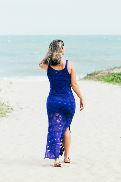 Portrait of young woman in blue dress relaxing on the beach - Photo, image