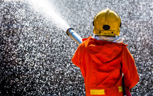 Firefighter using extinguisher and water from hose for fire fighting, Firefighter spraying high pressure water to fire with copy space. - Foto, Imagem